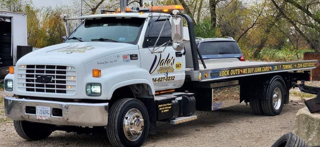 White tow truck with flatbed, parked outdoors.