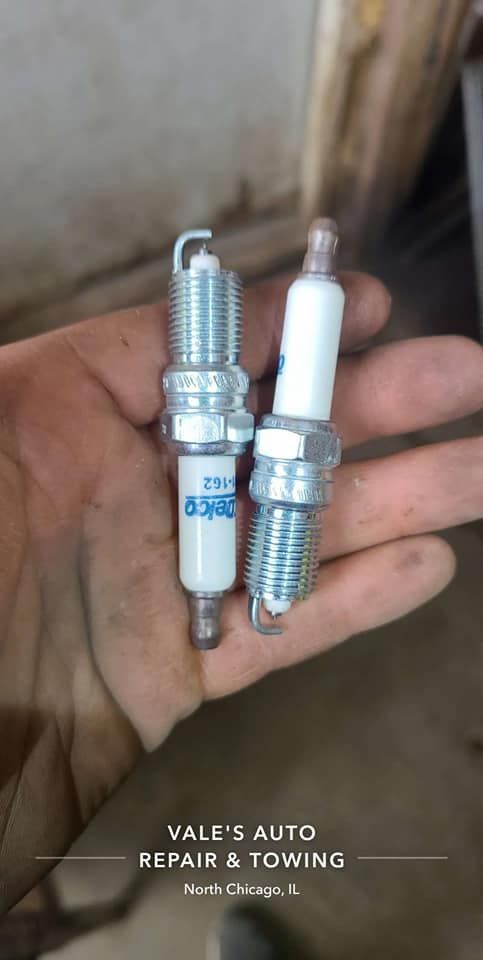 Two spark plugs held in hand. The old one is on the left and the new one is on the right.