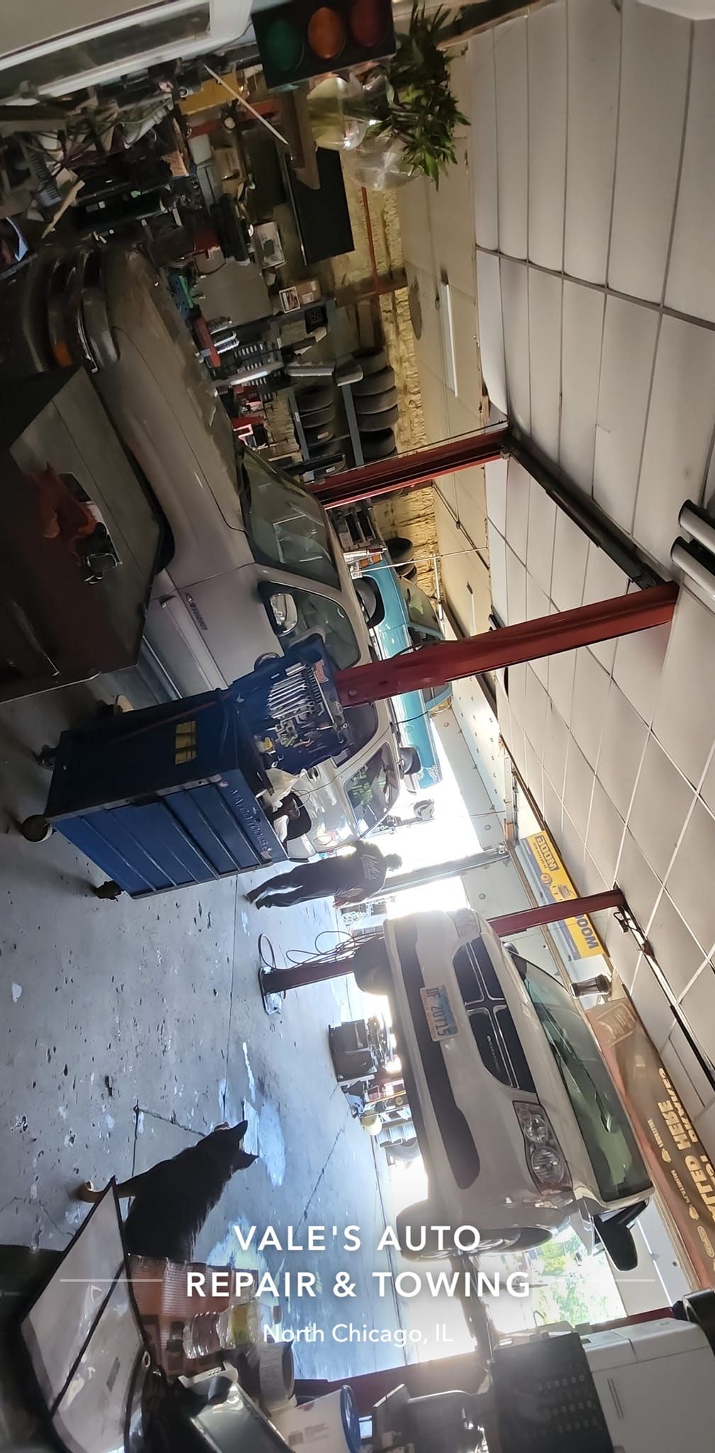 An auto repair shop interior with cars, tools, and a bay. Text on the bottom reads 