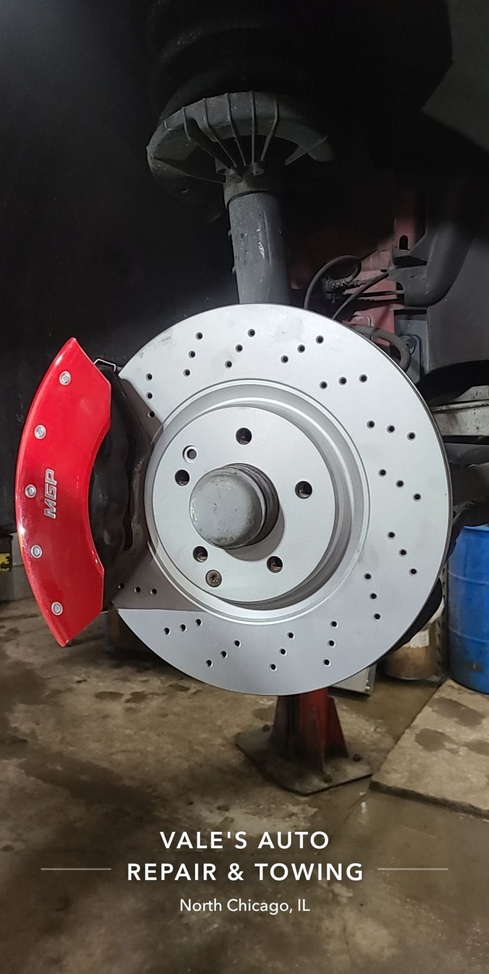 A car brake rotor and red caliper being repaired at Vale's Auto Repair in North Chicago, IL.