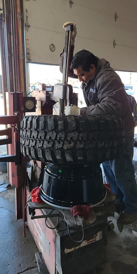 A person working on a tire and rim with a machine at a garage.