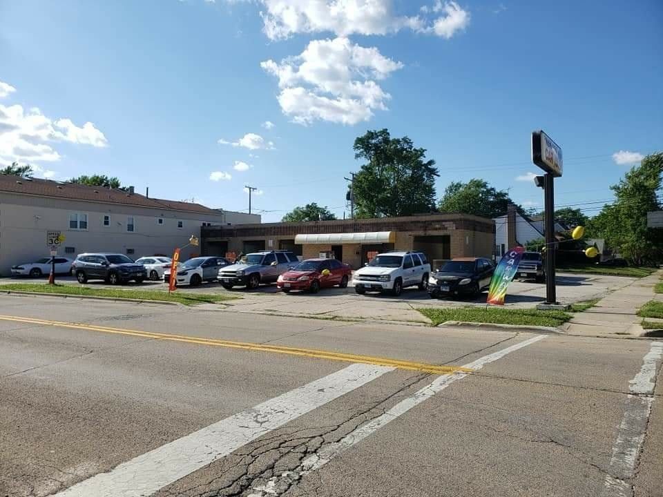 Cars parked outside a one-story brick building on a sunny street corner.