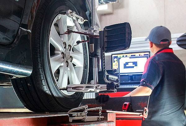 A mechanic using a computer to check the wheel alignment of a car in a garage.