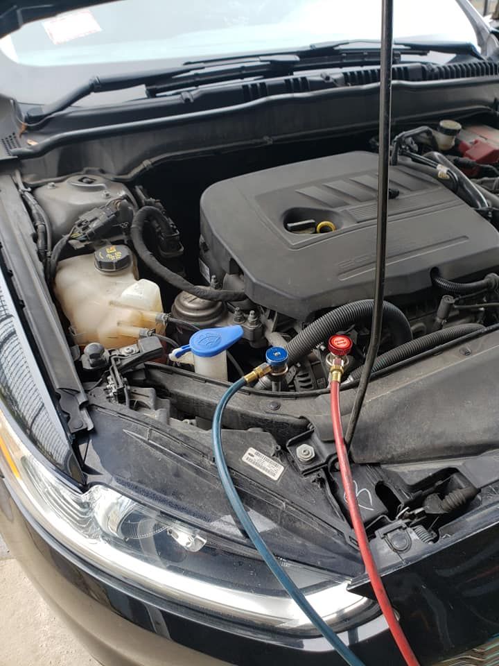 Car engine bay with hoses connected for AC service.