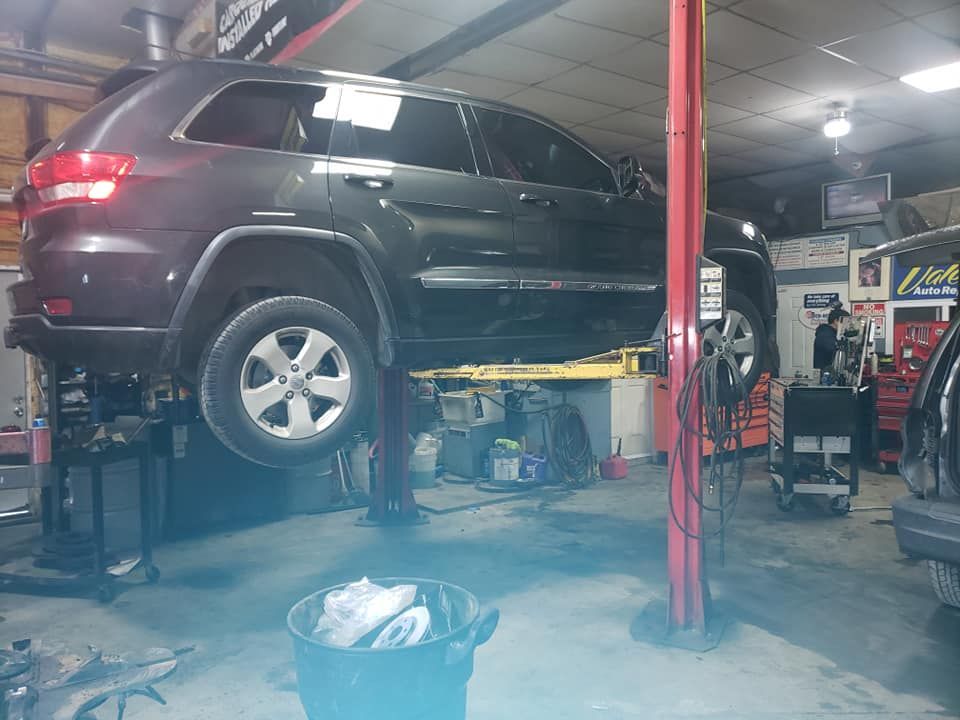 Jeep Grand Cherokee on a lift in a repair shop. A person stands beneath the vehicle.