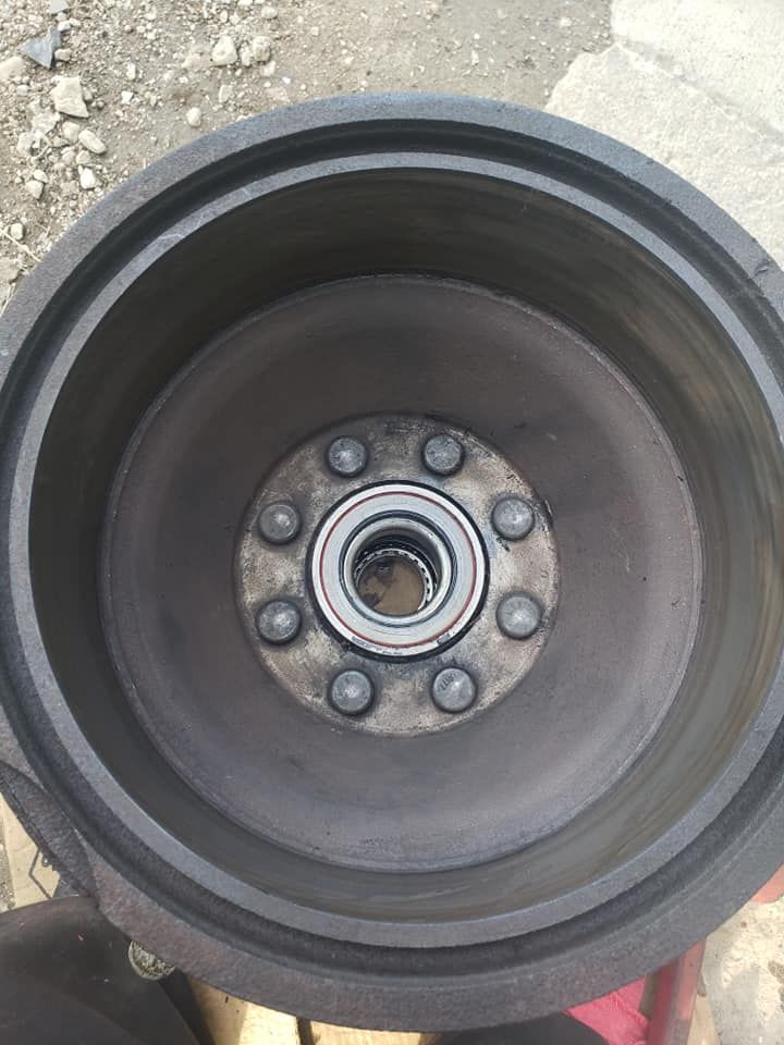 Black metal drum with a central hub containing a bearing and bolts.