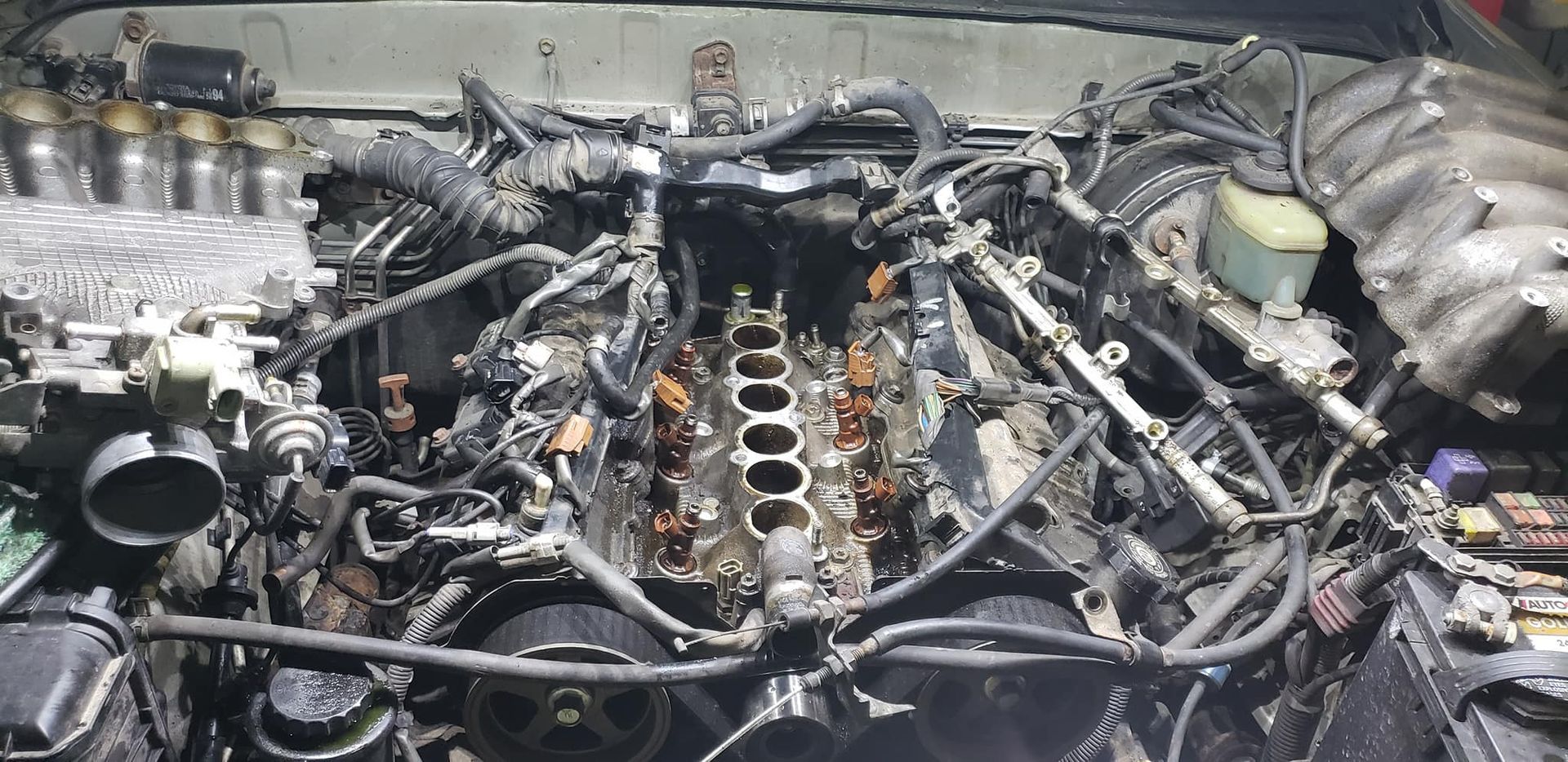 An engine with many wires and tubes removed, mid-repair. The heads and block are visible.