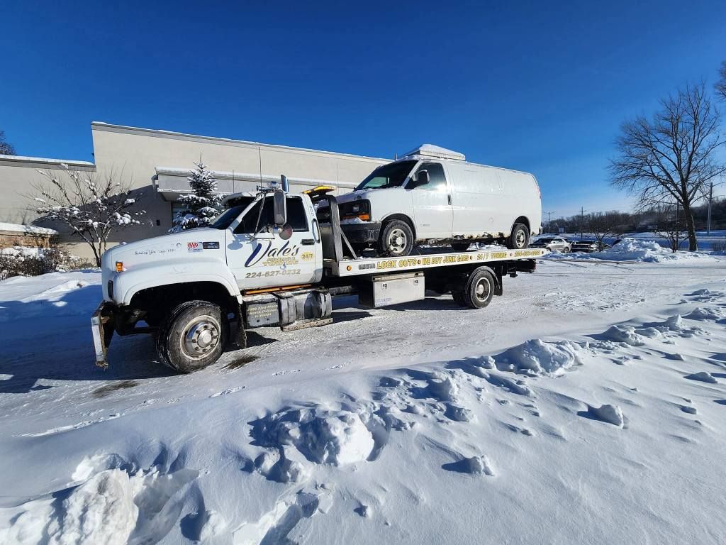 White tow truck hauling a white van on a snowy day.