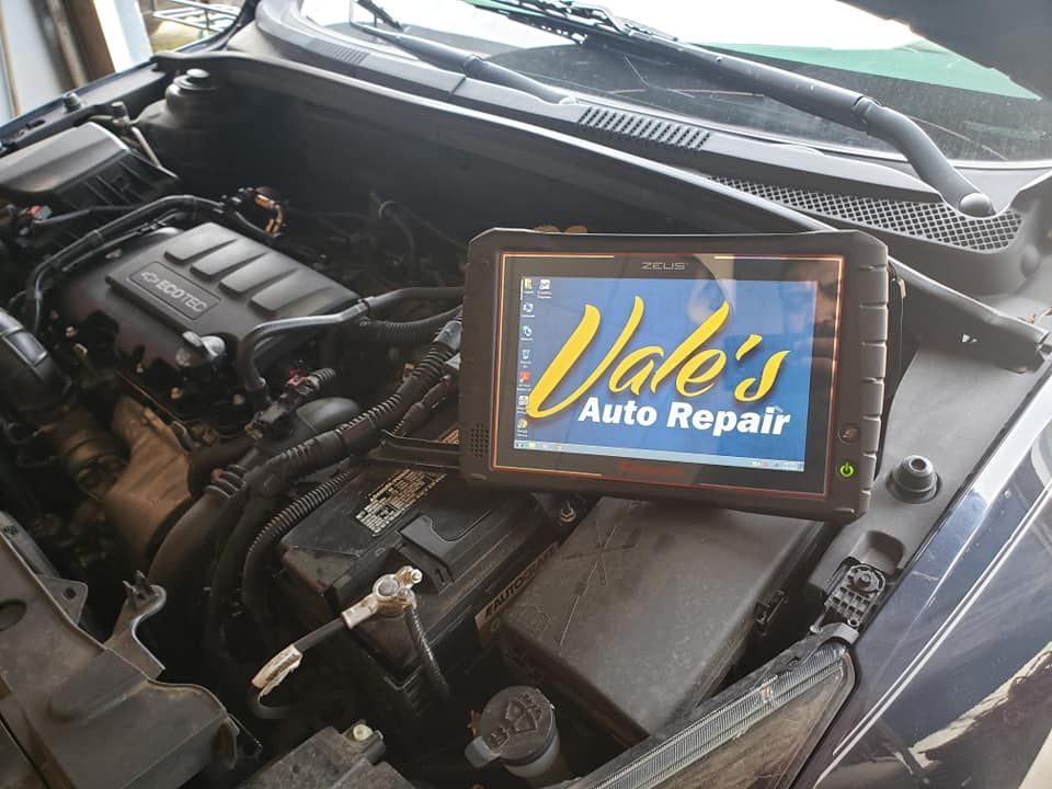 Car engine bay with a diagnostic tablet displaying 