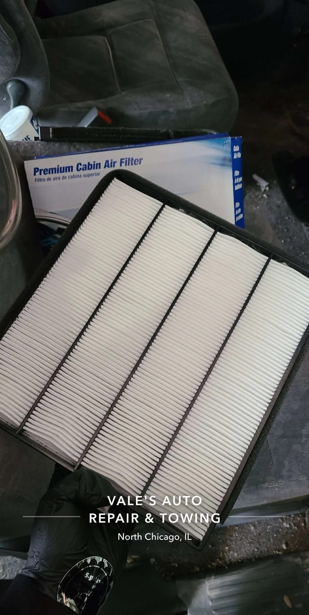 Car cabin air filter with box, sitting on the floor of a car.
