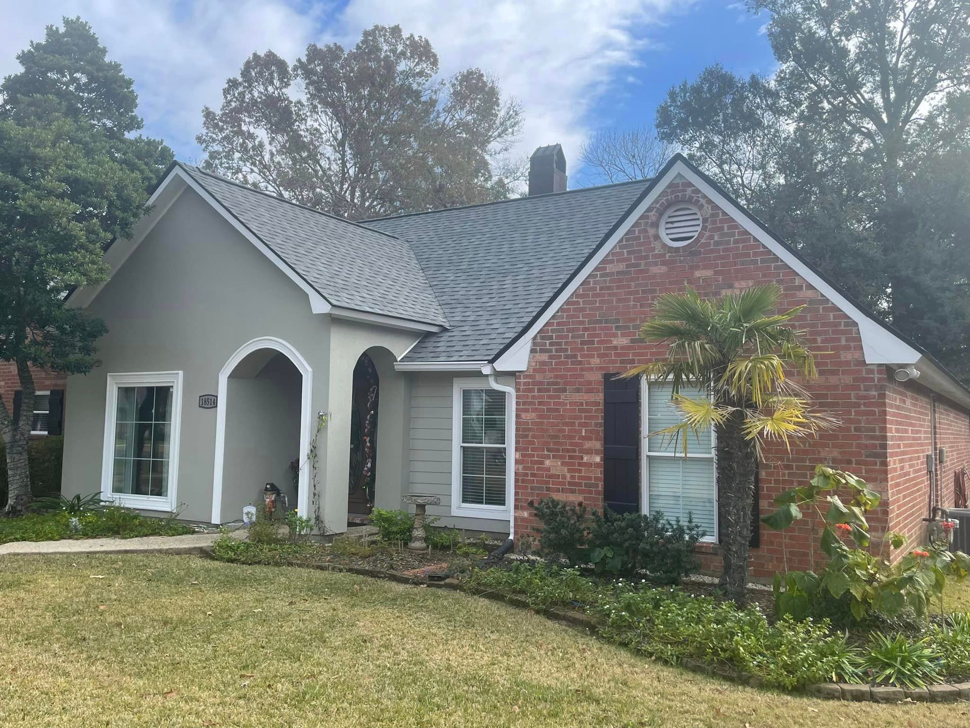 A brick house with a gray roof and white trim