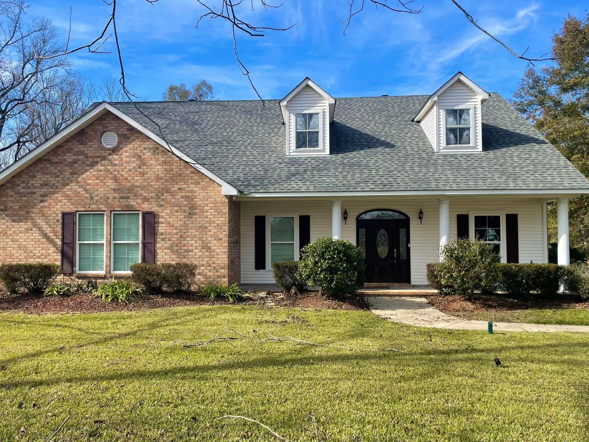 A large brick house with a gray roof and white trim