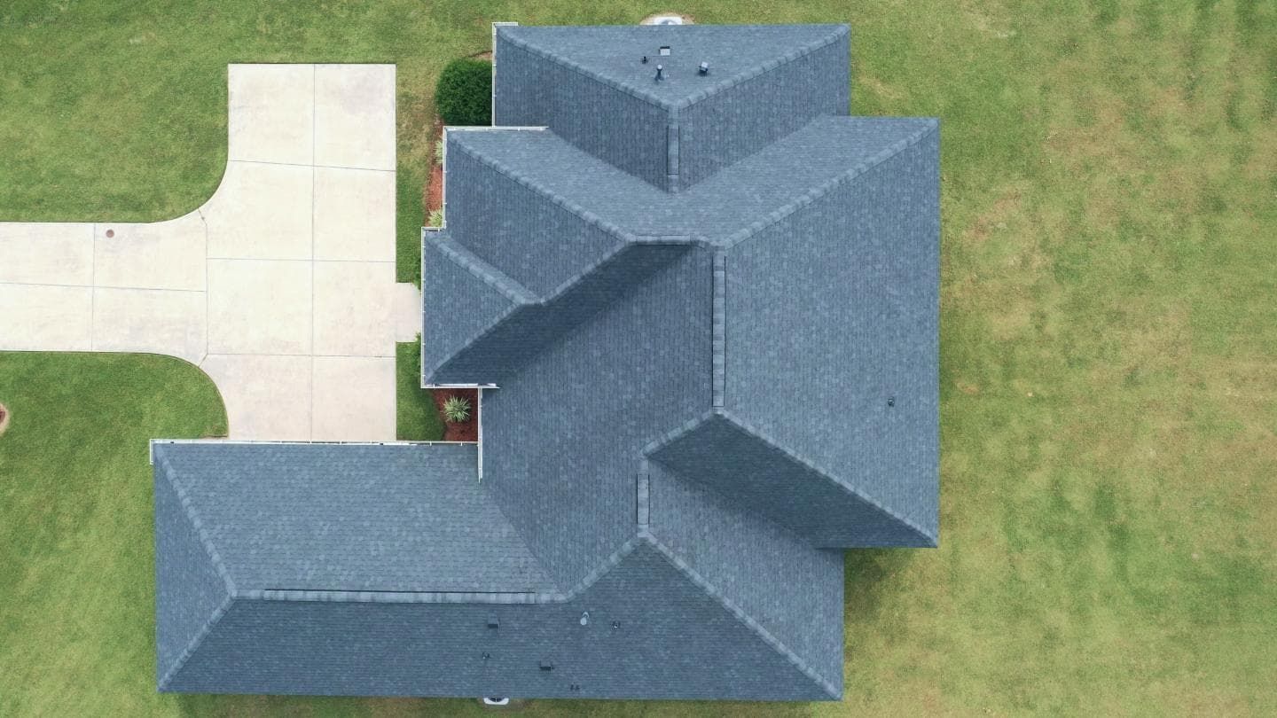 An aerial view of a house with a blue roof and a driveway