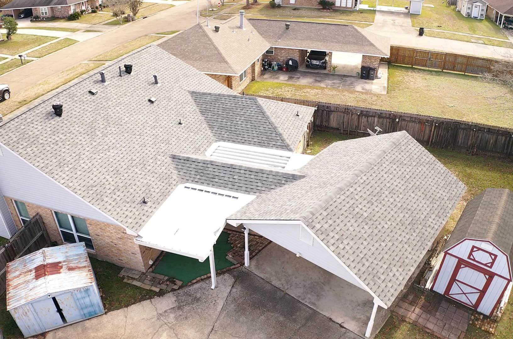 An aerial view of a house with a carport and a barn