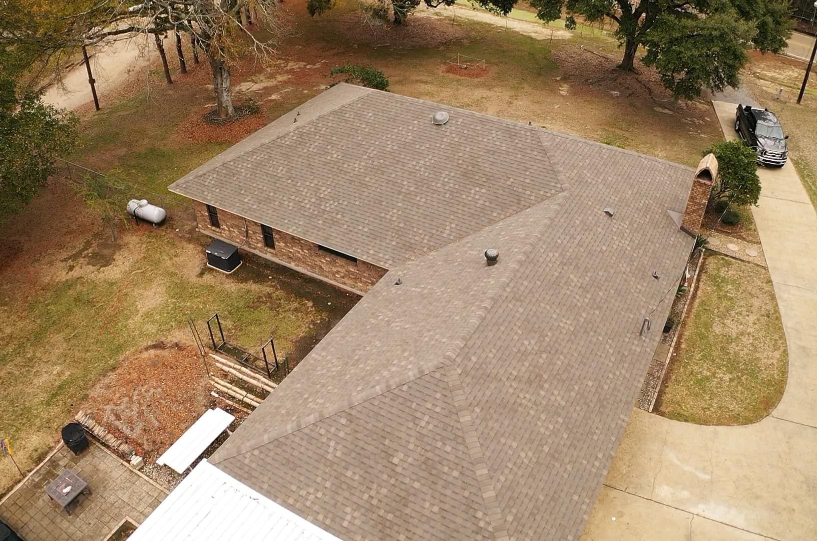 An aerial view of a house with a roof and a driveway