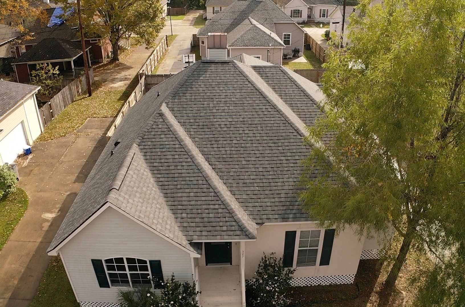 An aerial view of a white house with a gray roof