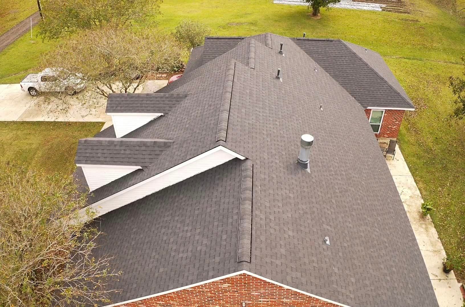 An aerial view of a roof of a house with a car parked in the driveway