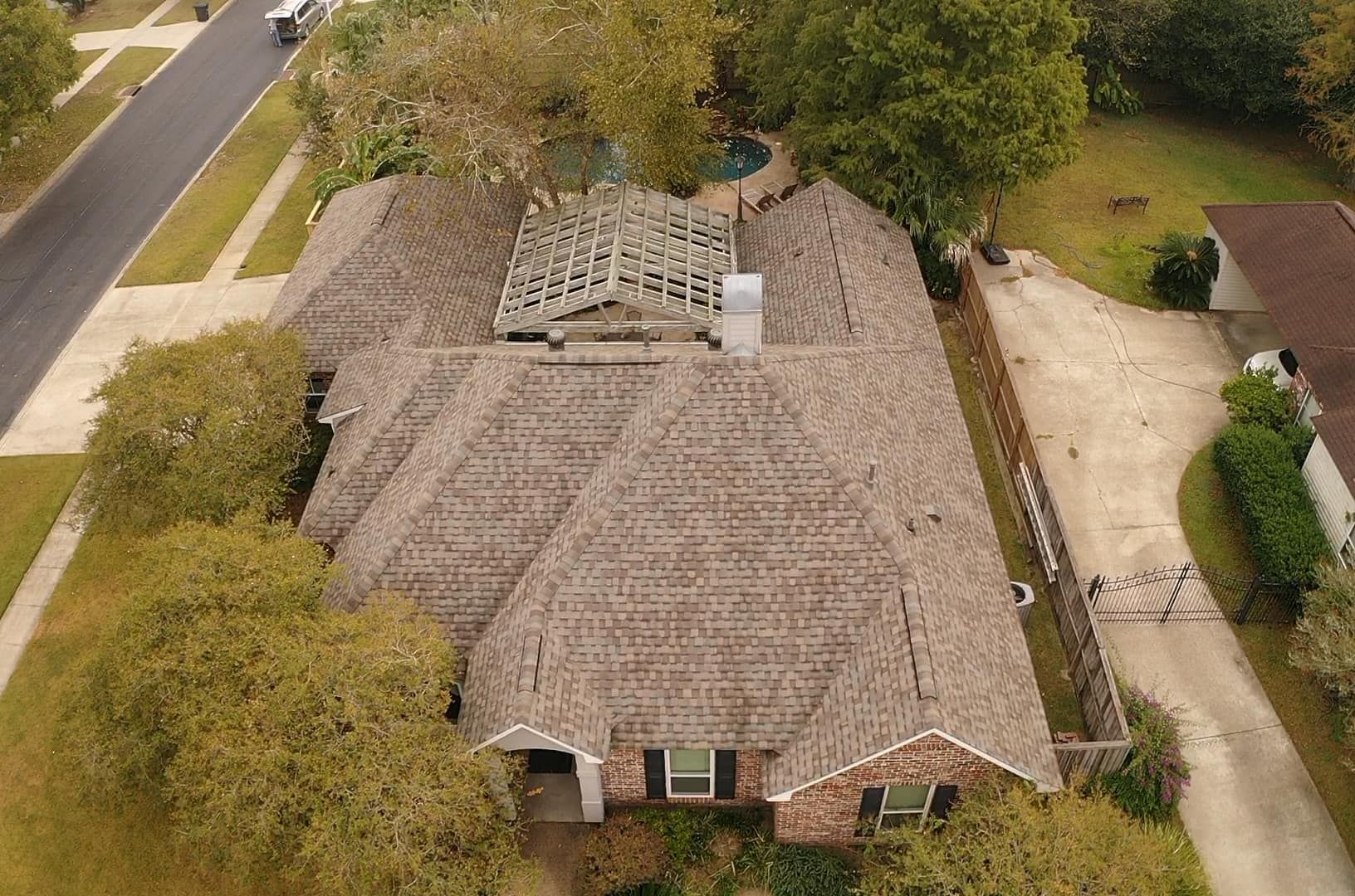 An aerial view of a house with a roof that is missing shingles