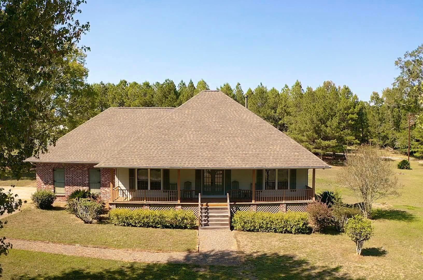 A house with a porch in the middle of a field