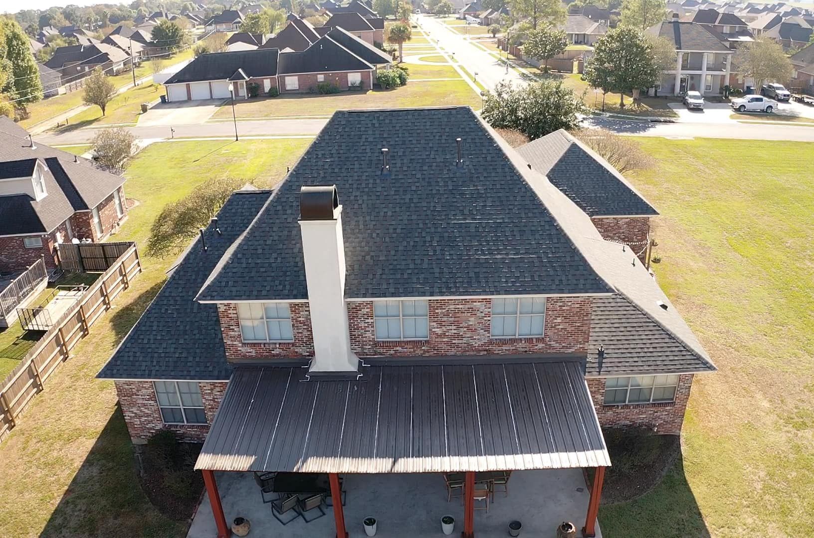 An aerial view of a large brick house with a black roof