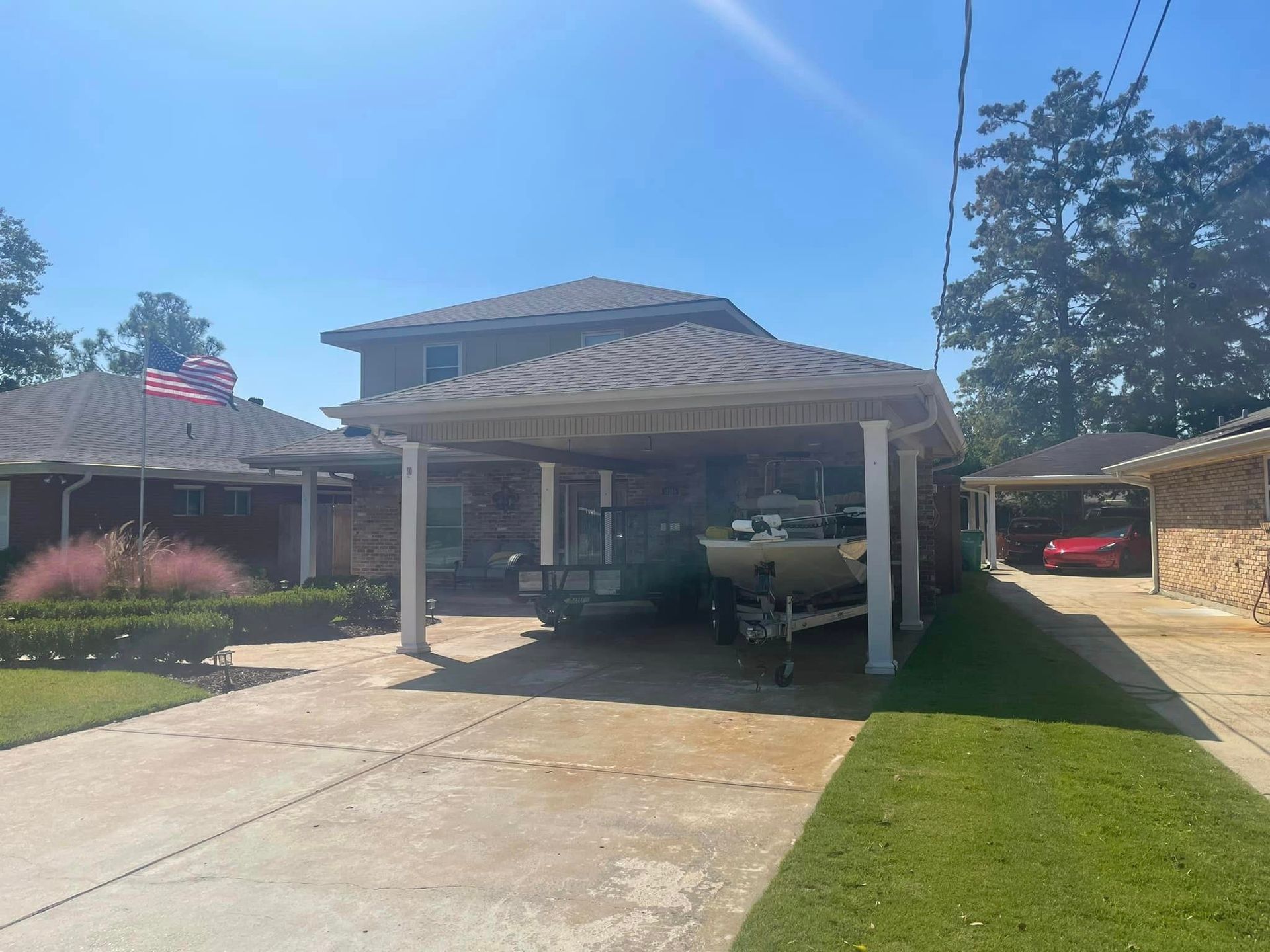 A boat is parked under a carport in front of a house