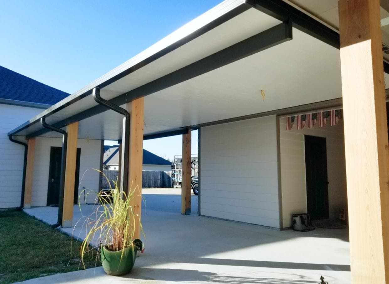 A house with a covered porch and a potted plant in front of it