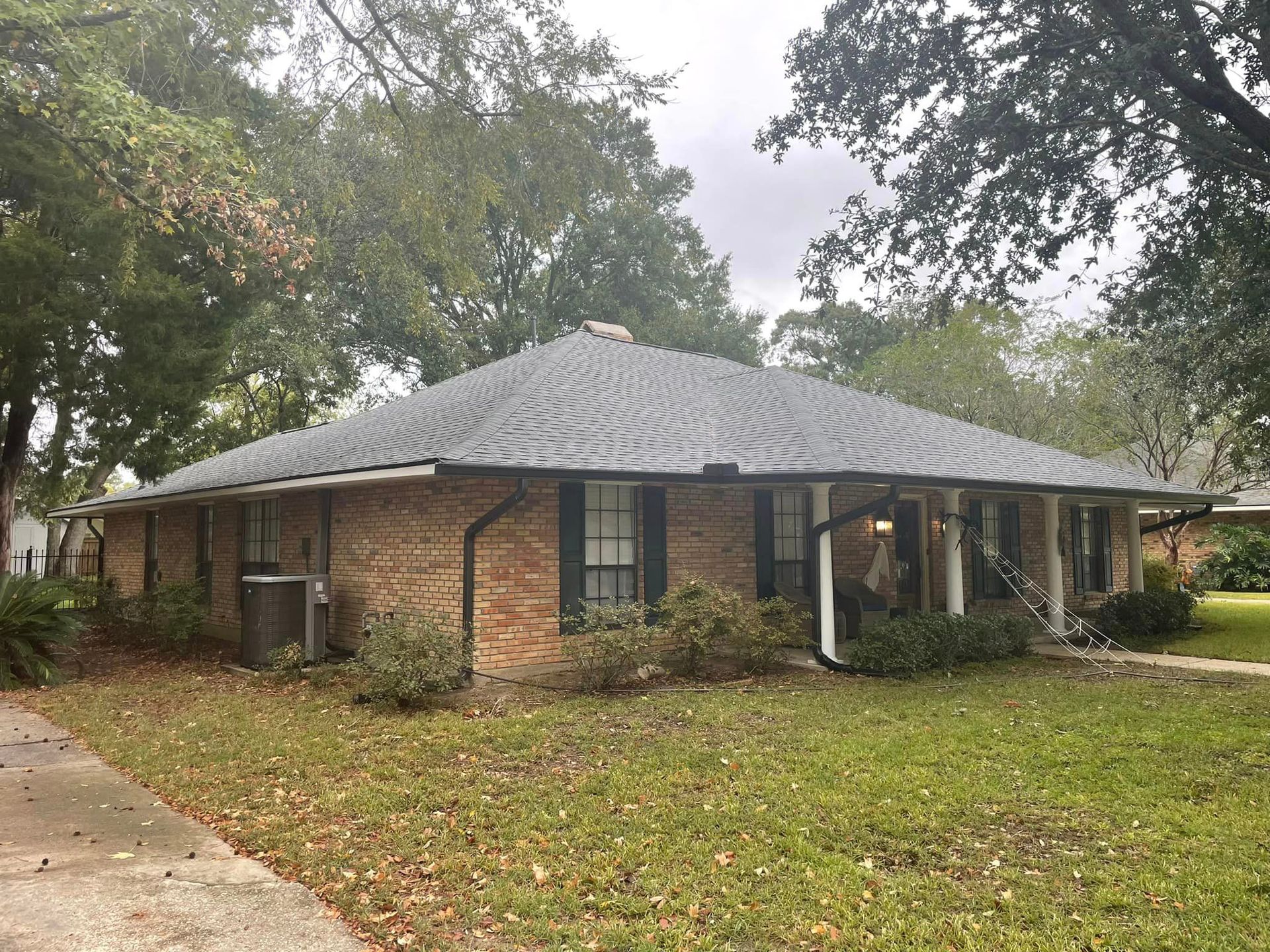 A brick house with a gray roof and black shutters