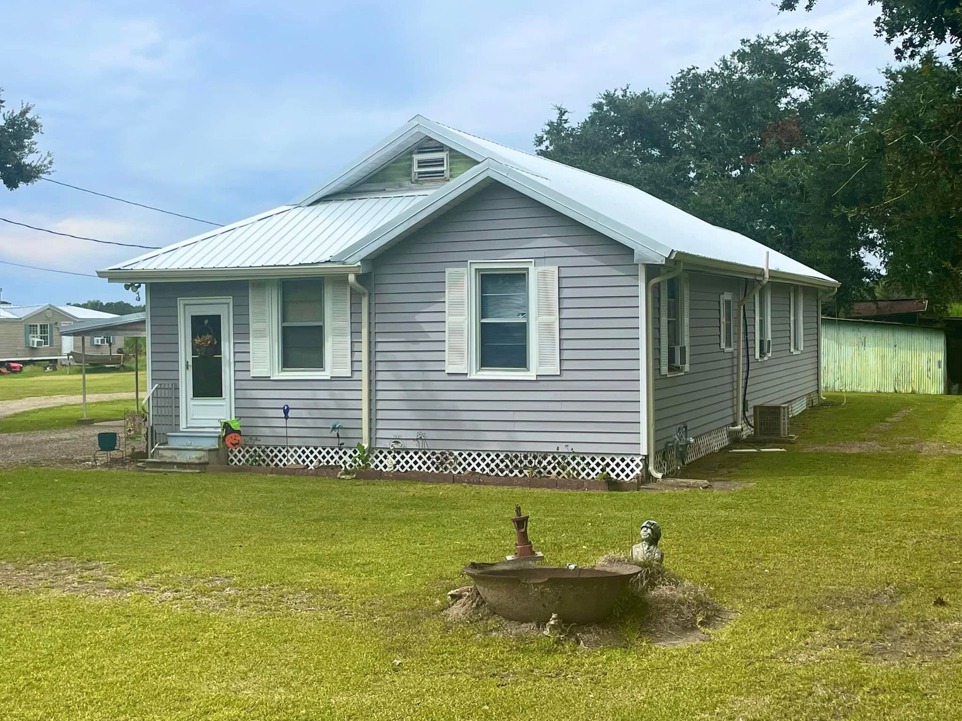 A small gray house with white shutters and a white roof