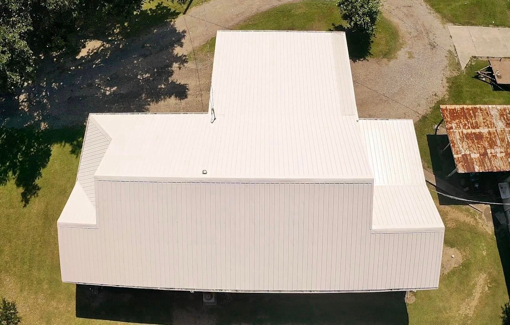 An aerial view of a white barn with a white roof