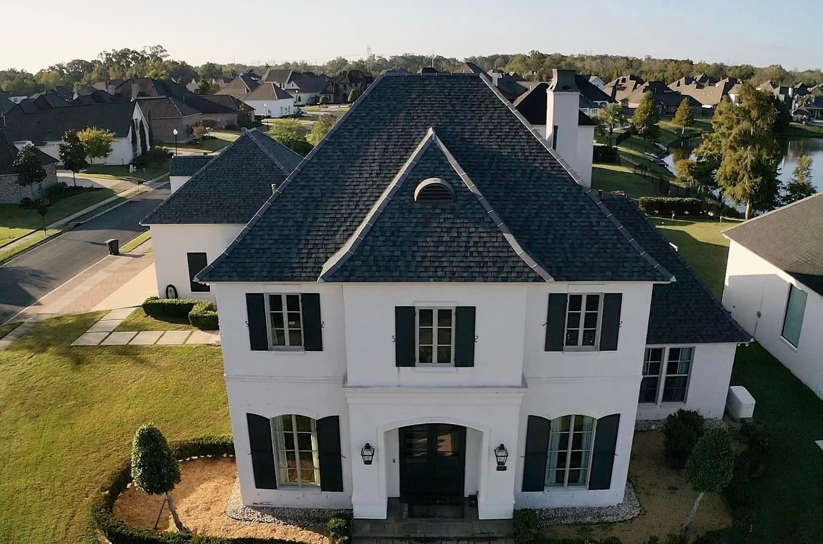 An aerial view of a large white house with black shutters