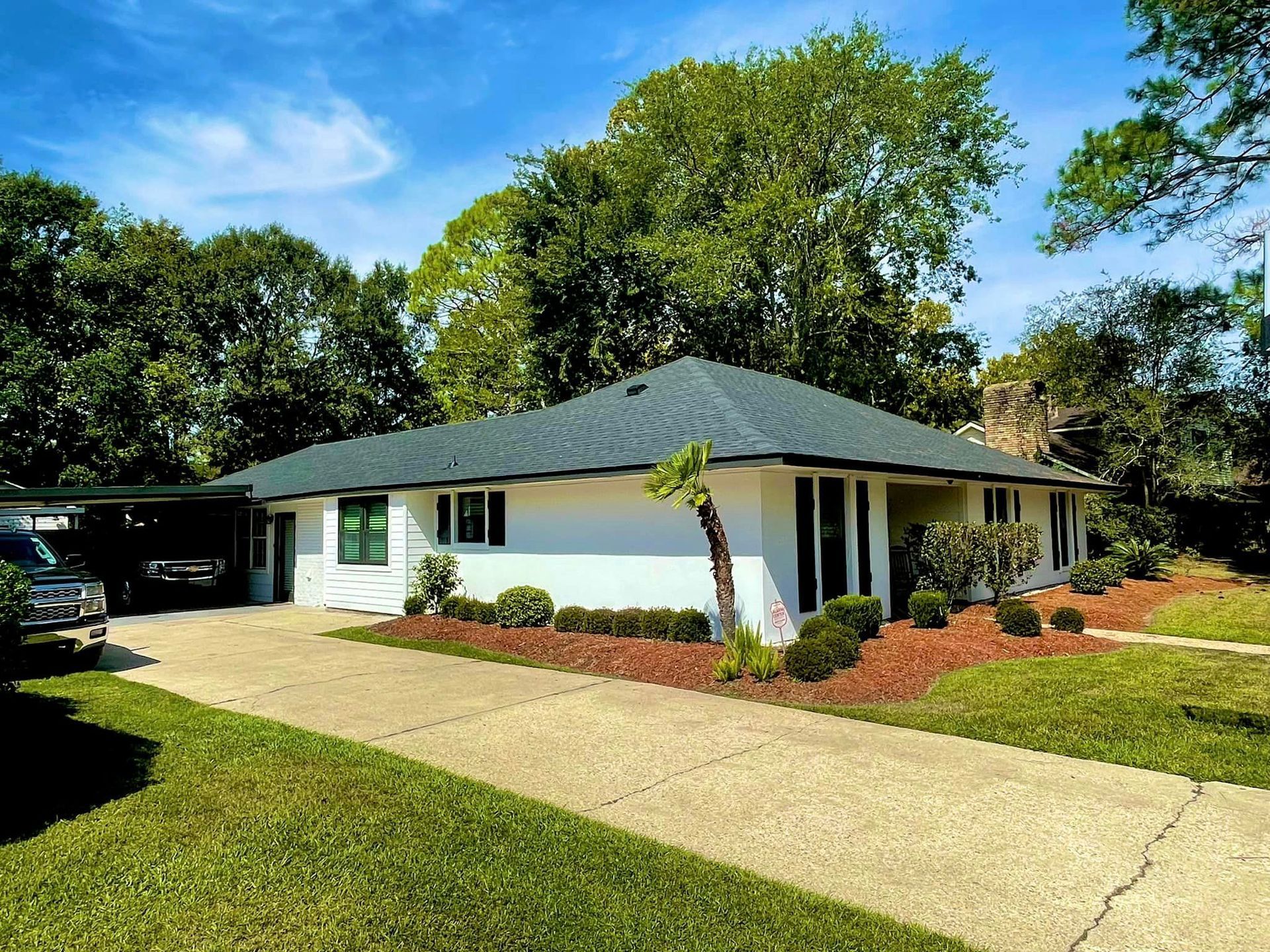 A white house with a green roof and a car parked in front of it