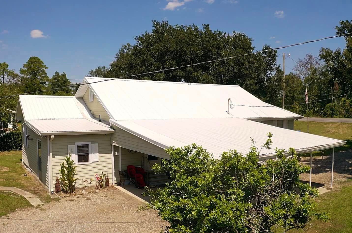 A white house with a white roof is surrounded by trees