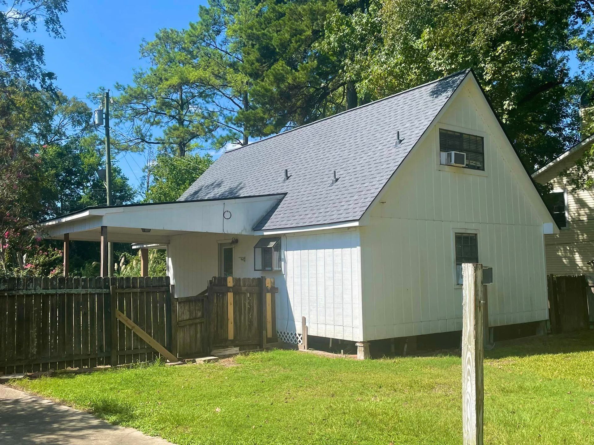 A white house with a gray roof and a wooden fence