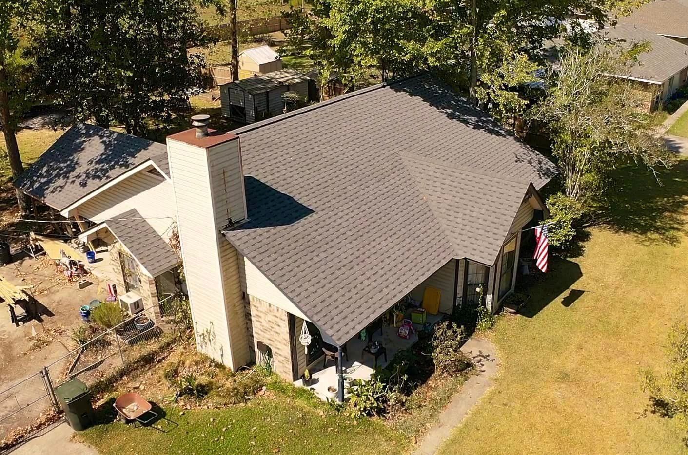 An aerial view of a house with a gray roof and a chimney