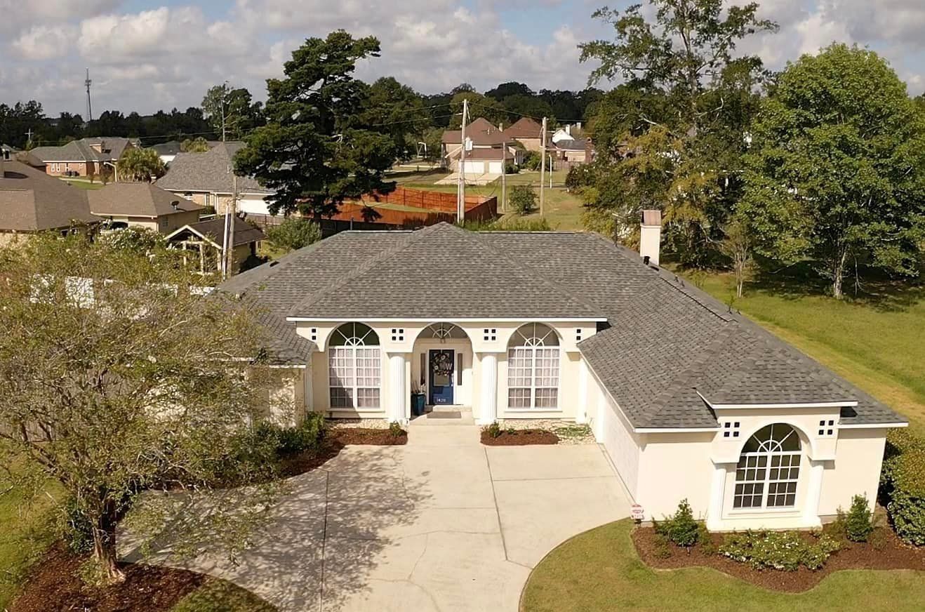 An aerial view of a white house with a gray roof