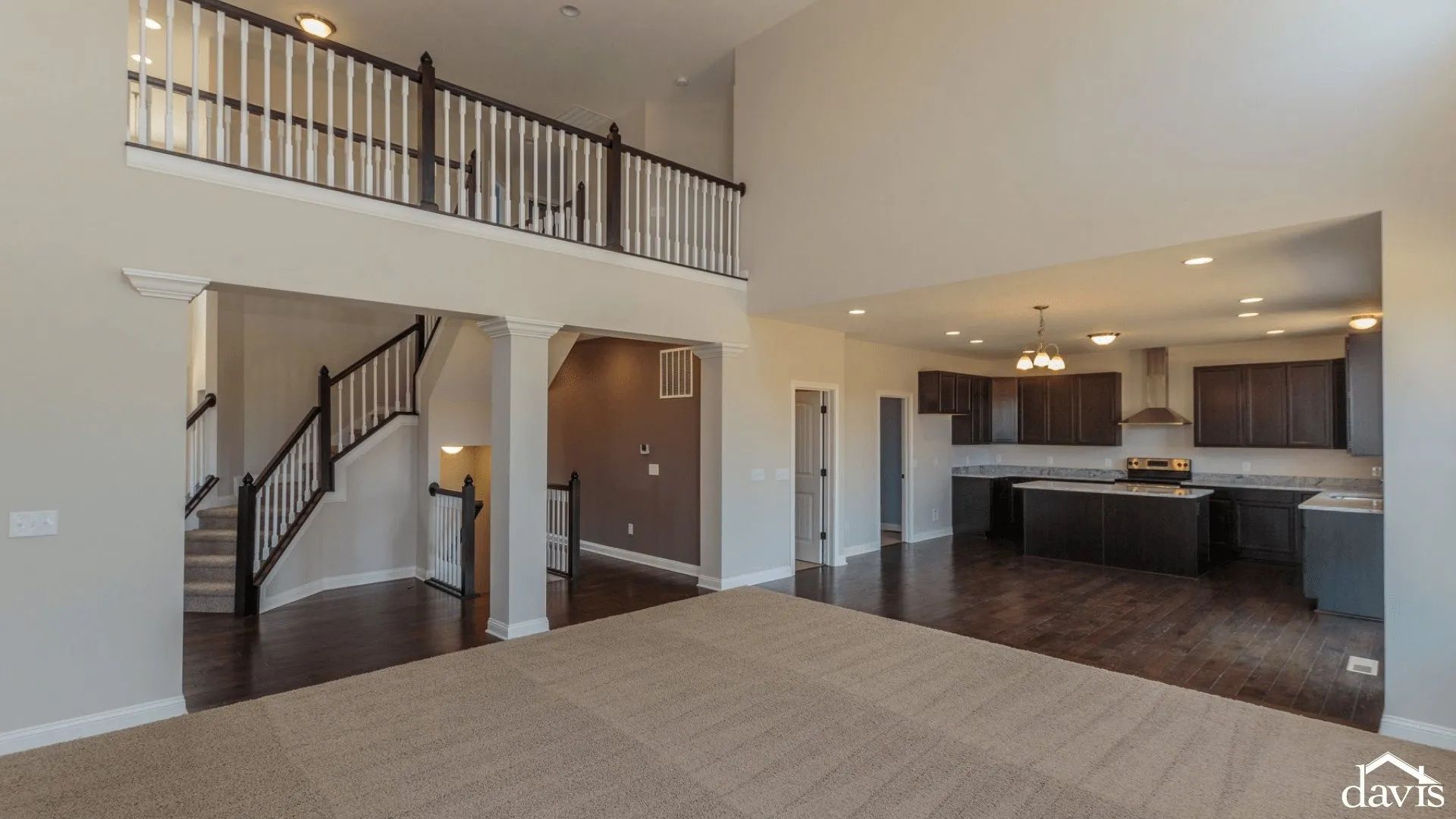 A large empty room with a balcony and stairs in a house.