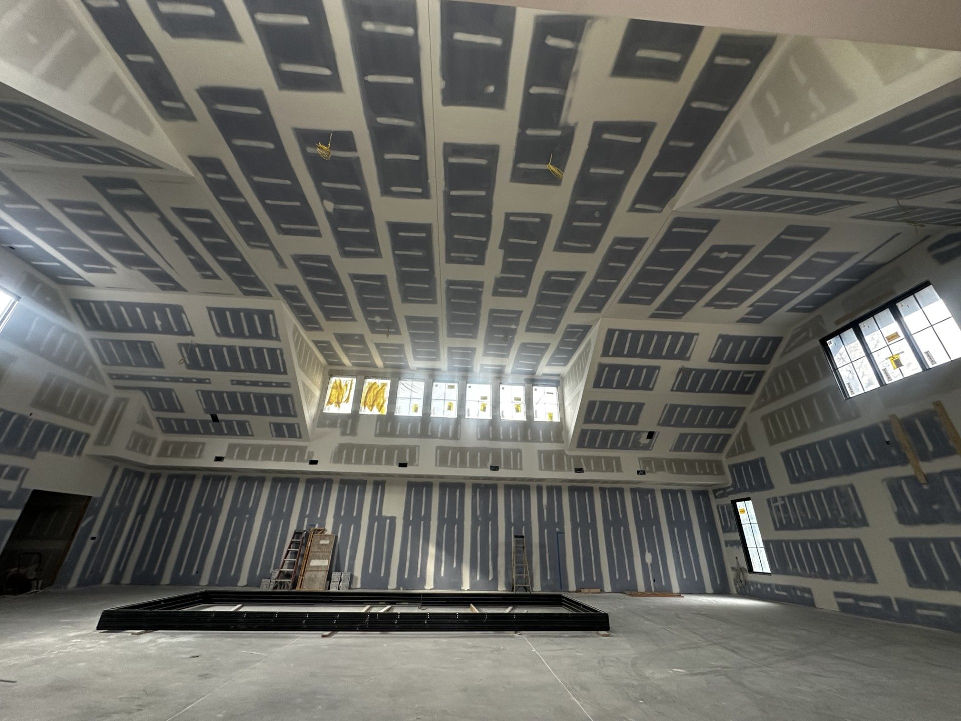 Interior of a room under construction, with exposed drywall panels on the walls and ceiling.