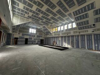 Interior of a large unfinished room with exposed drywall on walls and ceiling.
