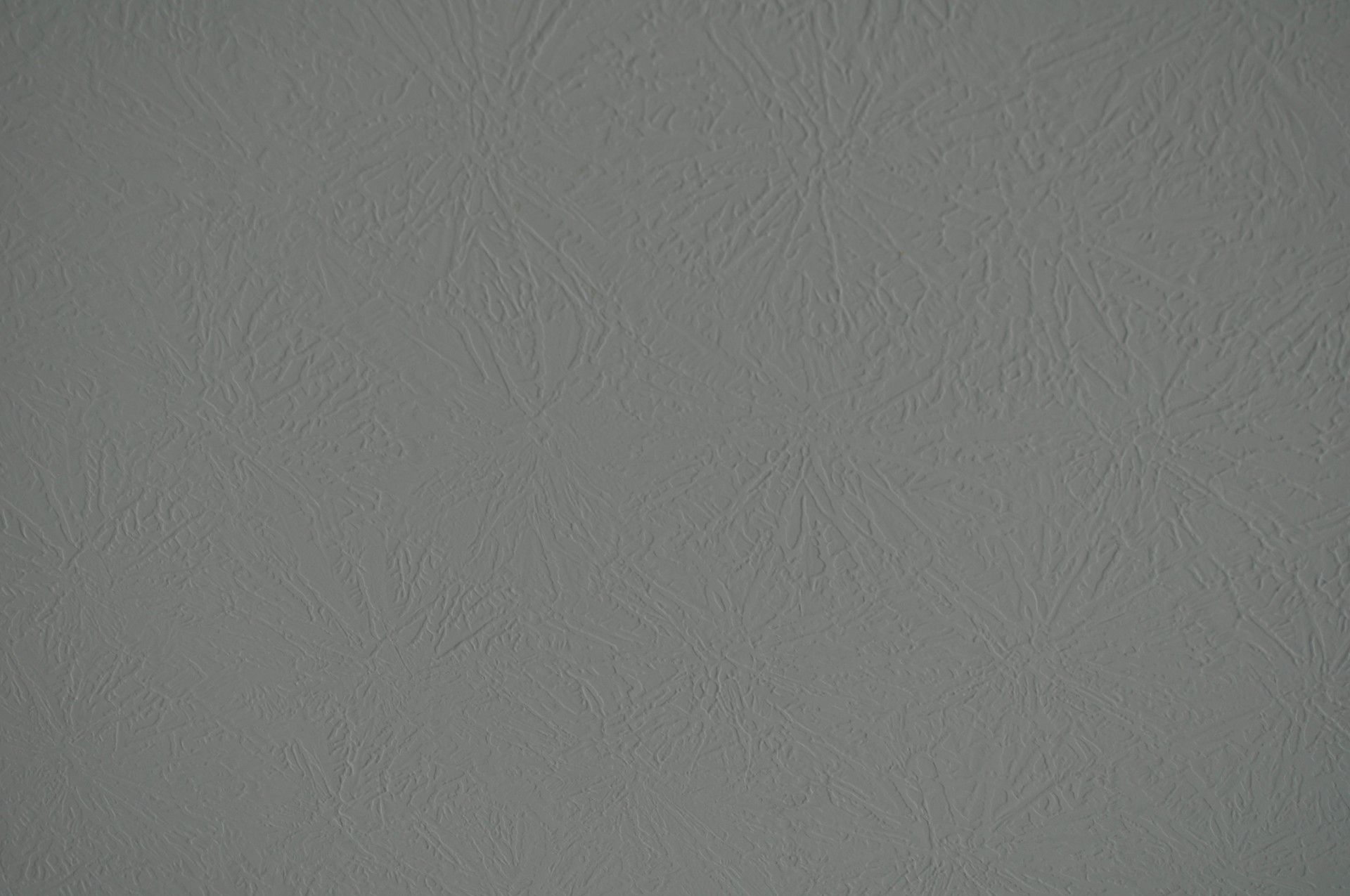 A light gray textured wall with a subtle, repeating fan-shaped pattern embossed across the surface.