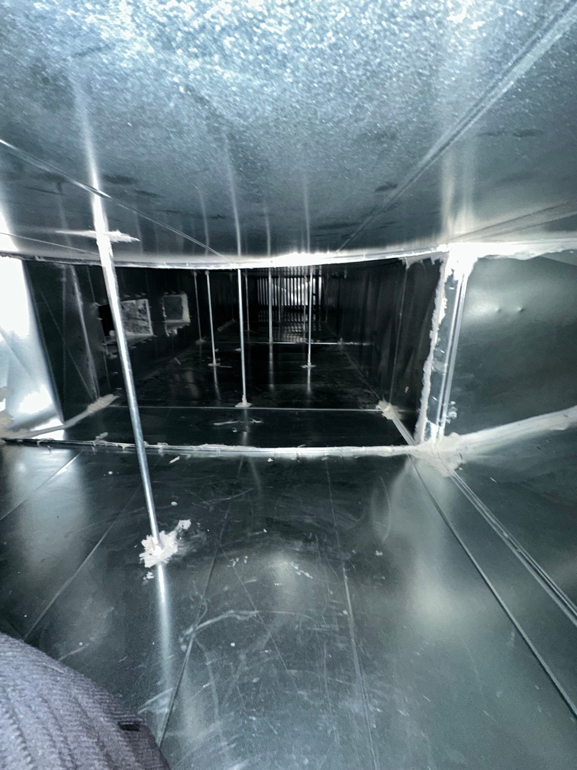 Inside of a rectangular air duct, constructed of shiny metal.