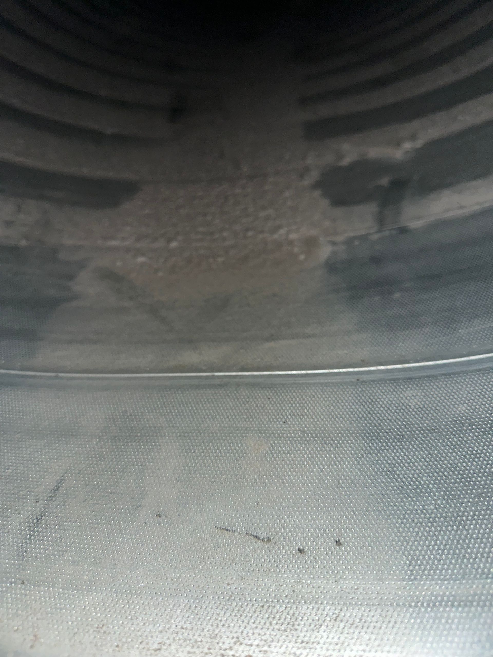Inside view of a metal duct, with visible seam and some discoloration near the top.