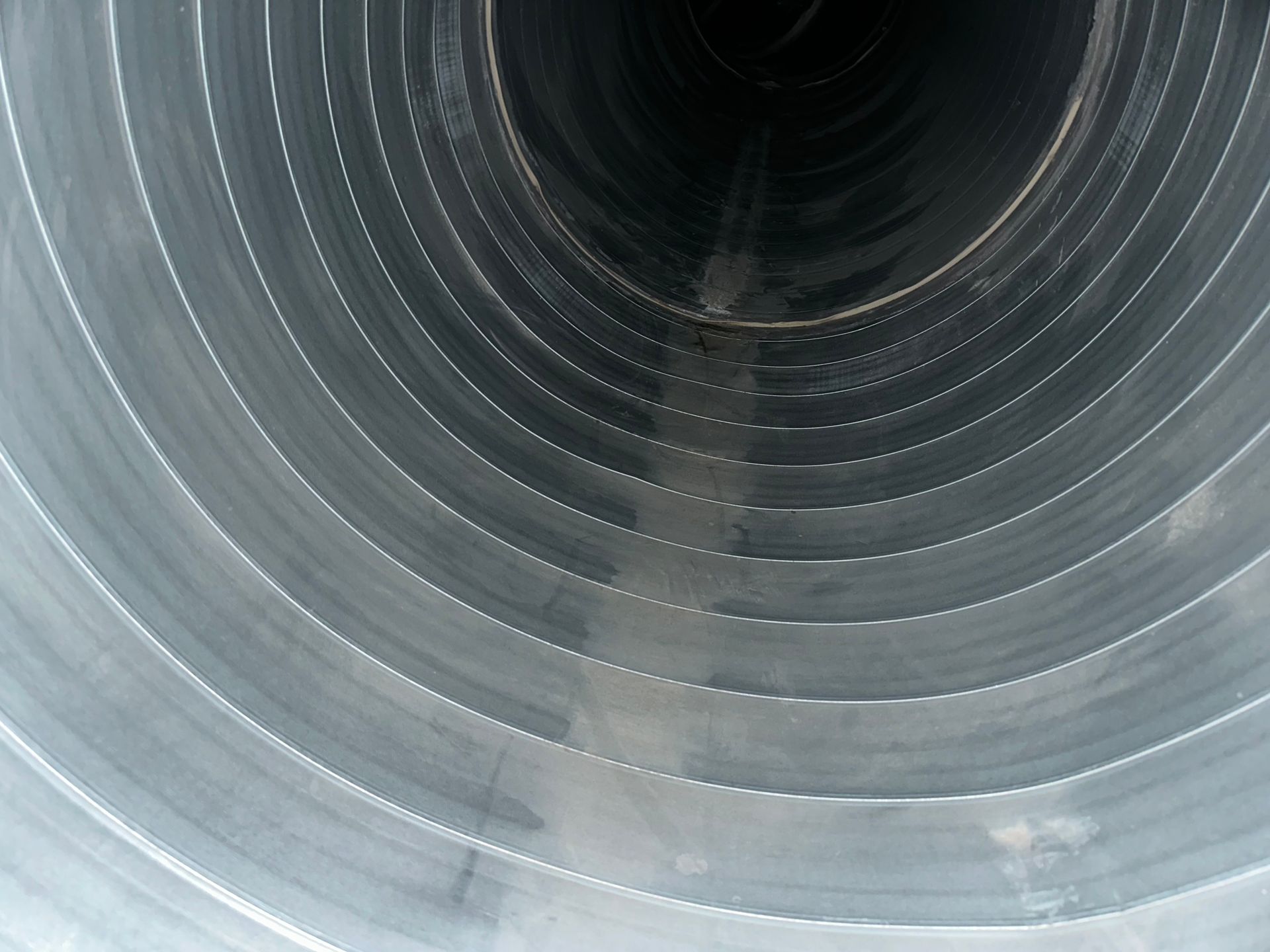 Inside view of a large, corrugated metal pipe, appearing to recede into darkness.