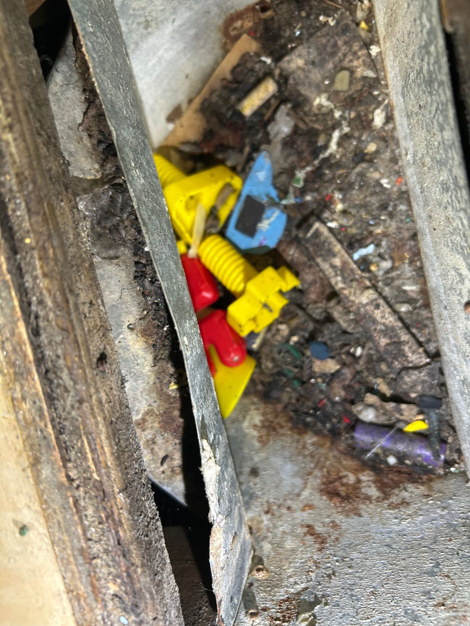 Pile of debris with colorful plastic pieces and wood fragments in a crevice.