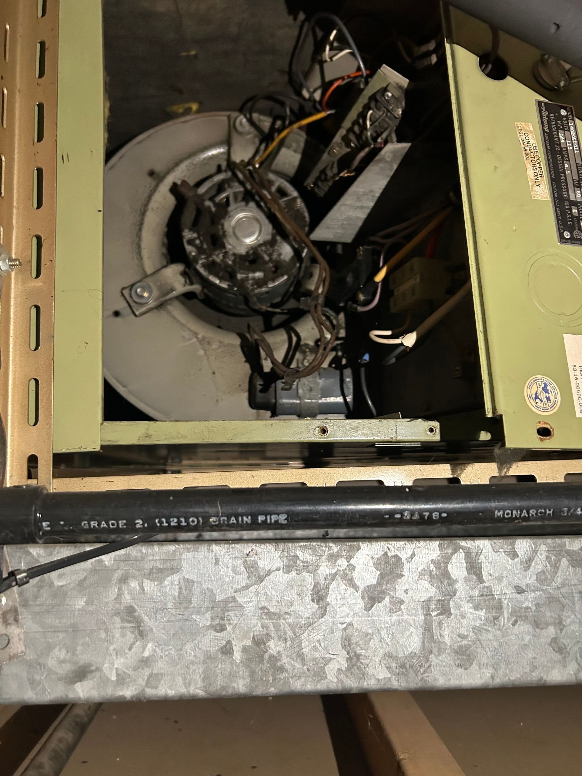 Overhead view of a damaged furnace blower motor and components, set in a metal housing.