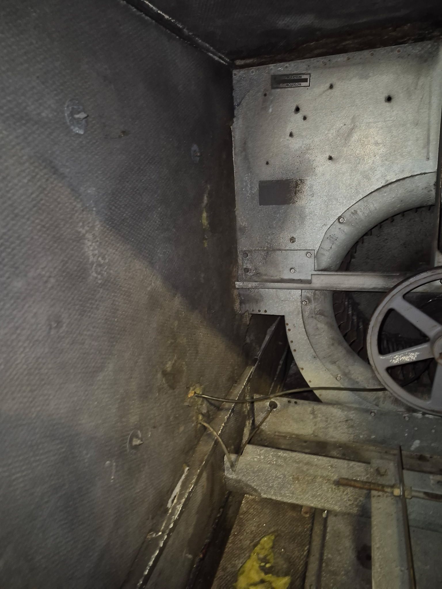 Inside of a dark, metallic structure; a large wheel and various mechanical components.