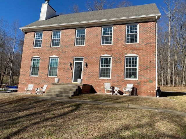 red and brown brick house with white patio furniture and cement stairs