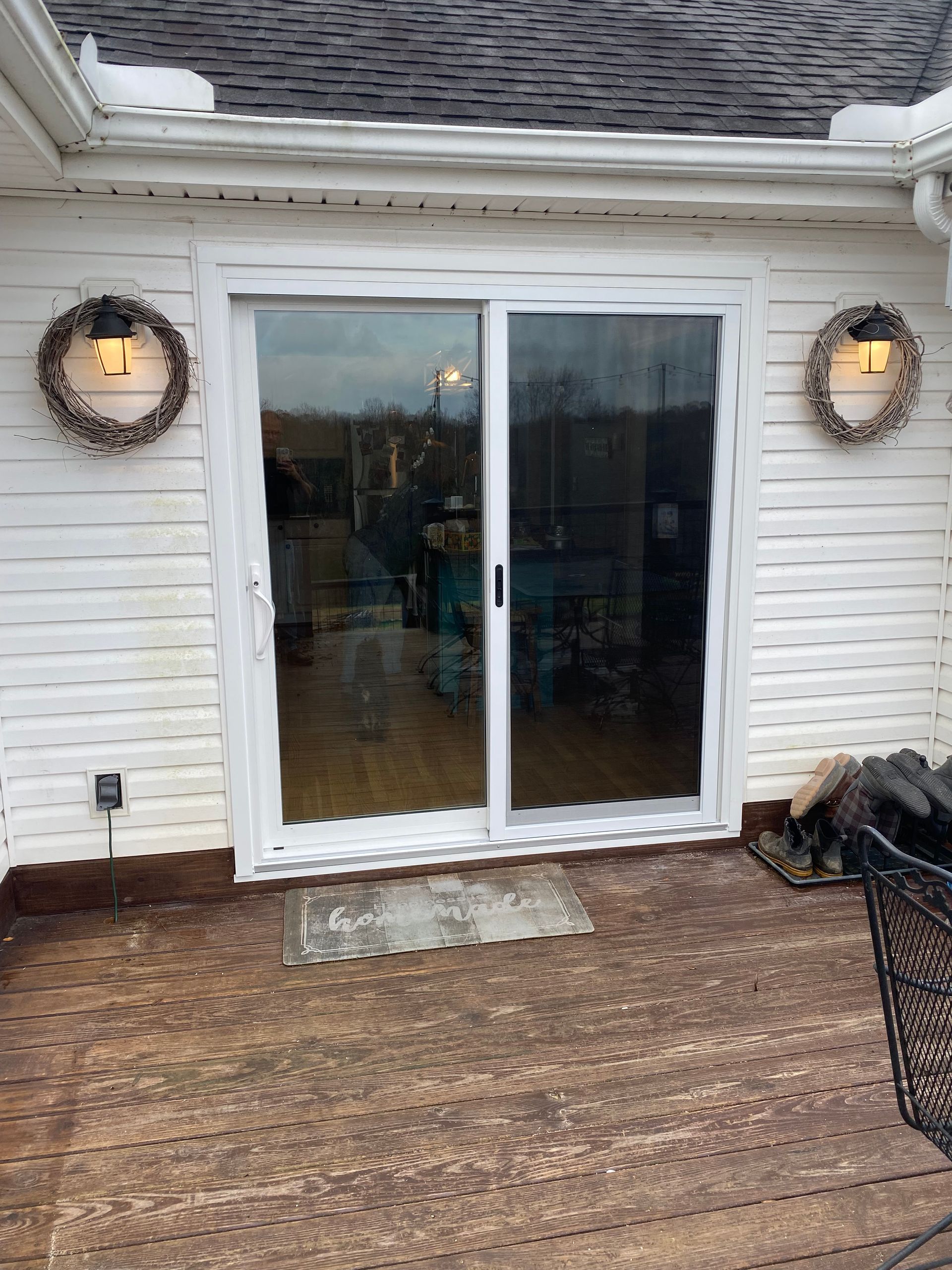 White sliding glass doors on a deck, flanked by wreath lights.