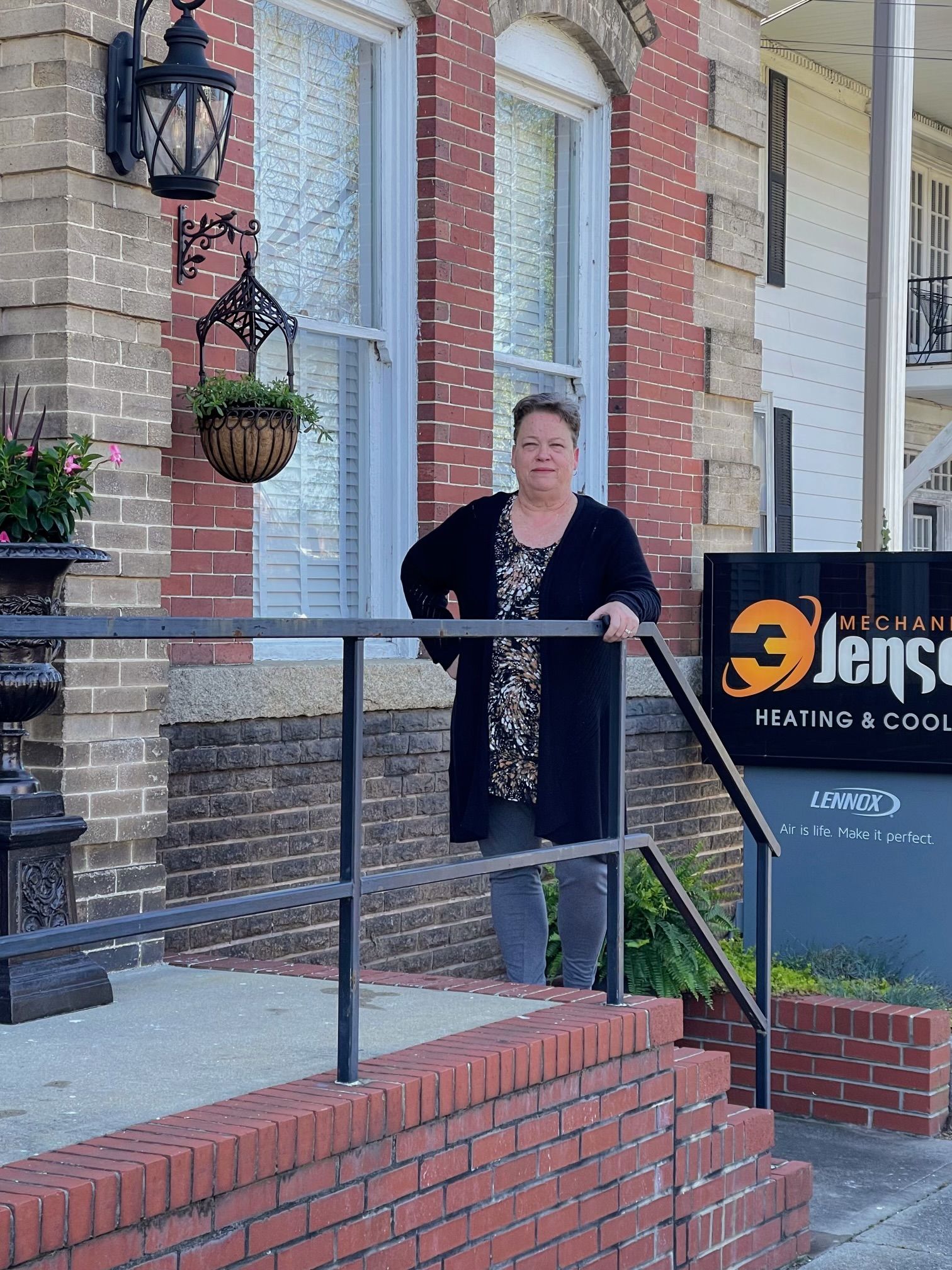 Woman standing on steps in front of a brick building; sign for 