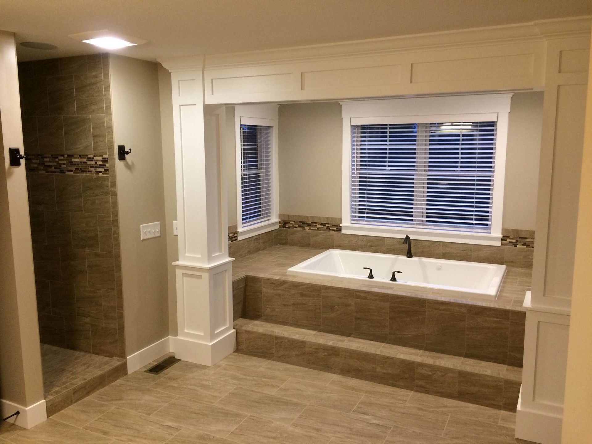 A bathroom with a tub , shower , and window.