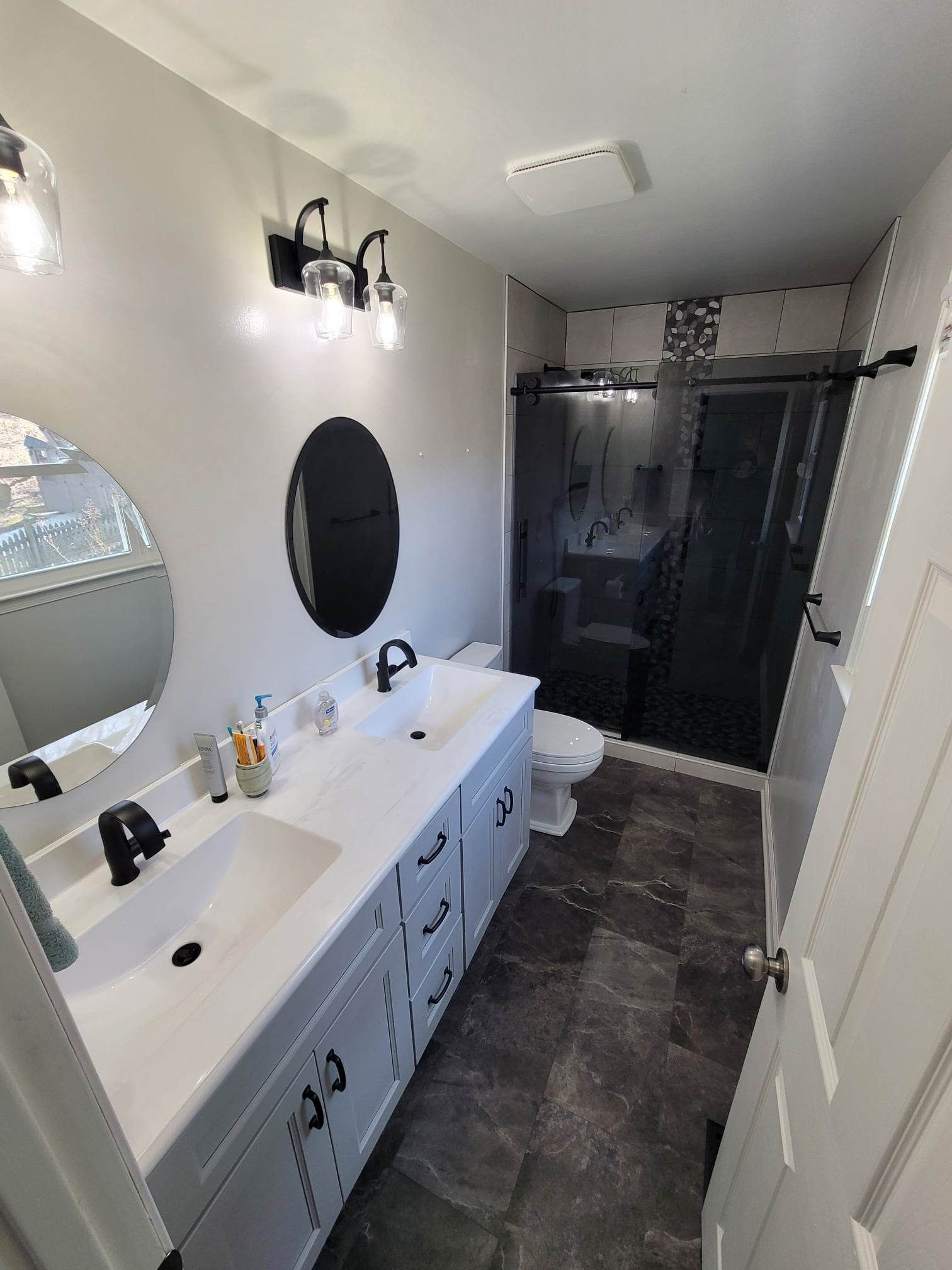 A bathroom with two sinks , a toilet , and a mirror.